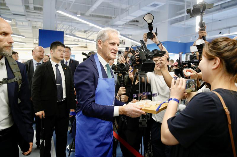 Norway’s PM Turns Fishmonger in Shanghai, Seeks Deeper Ties With China in EVs, Shipbuilding